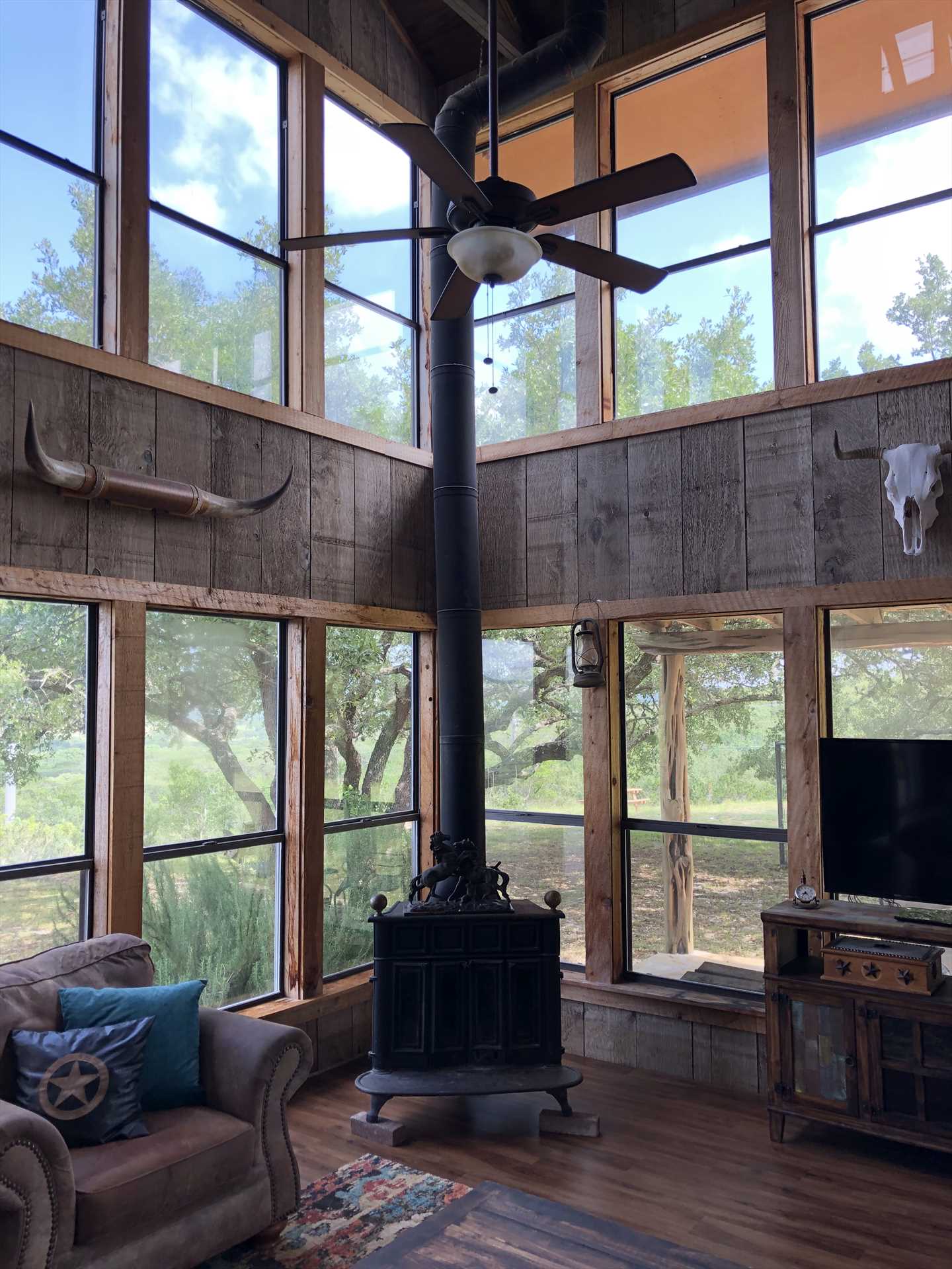                                                 The two-story-tall living area invites tons of natural light into the rustic space, and views of the Hill Country that have to be seen to be believed.