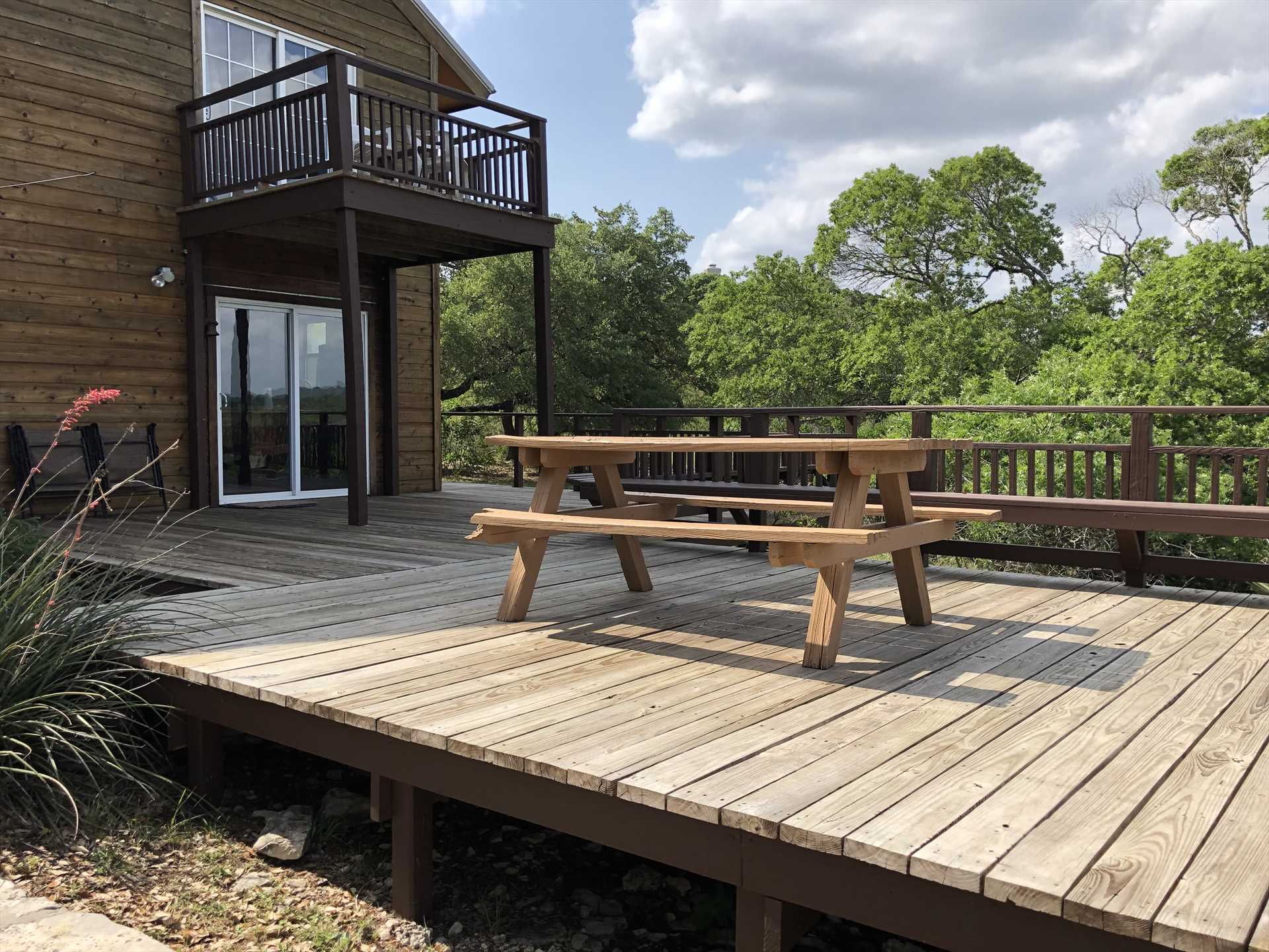                                                 The upper level of the back deck features a picnic table and bench-style seating. Just a few steps down from here is your private hot tub!