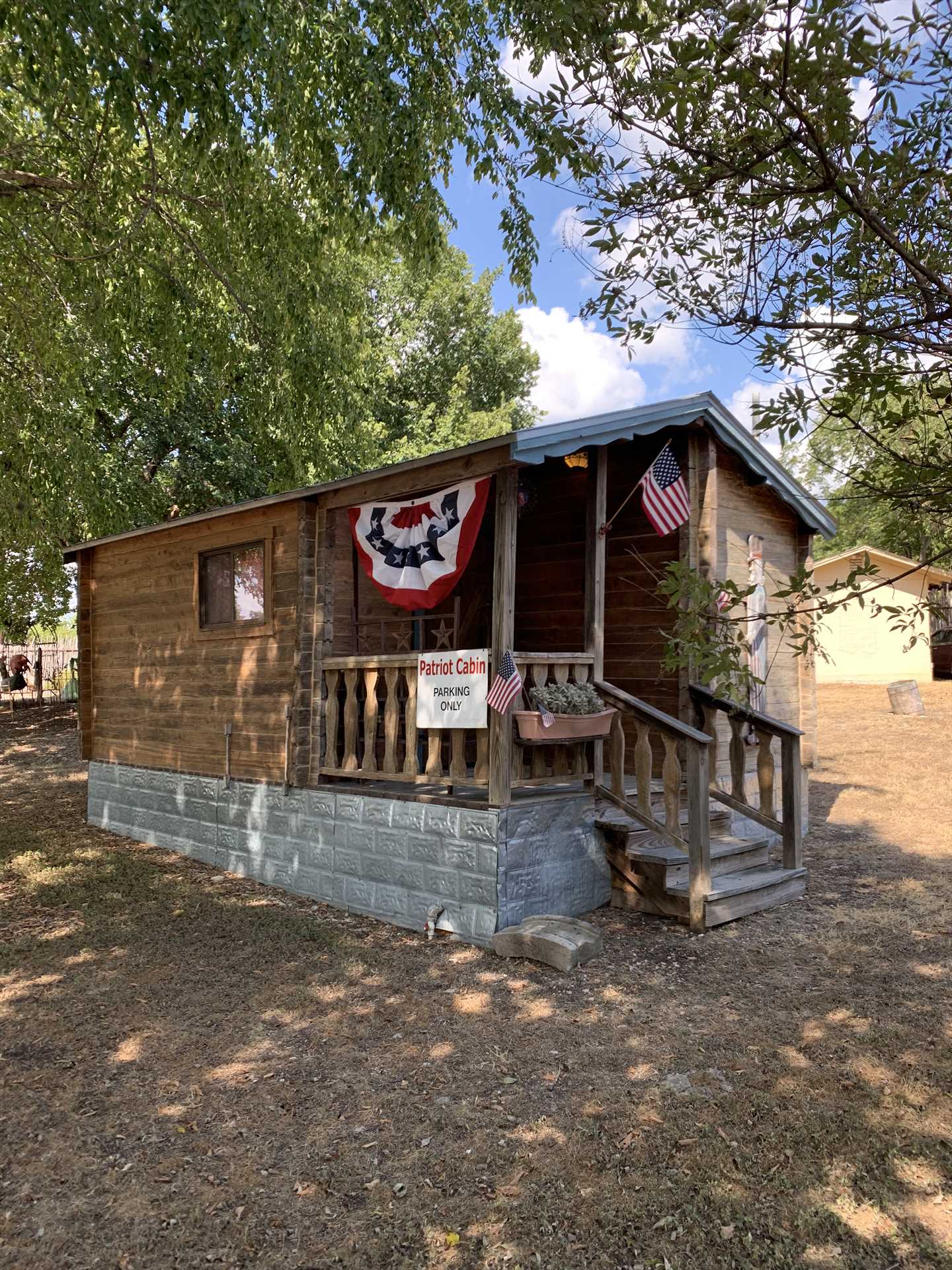                                                 Outside the Patriot Cabin, you'll find a cozy shaded porch, enclosed play area for kids and pets, and a charcoal grill and fire pit for outdoor meals and snacks!
