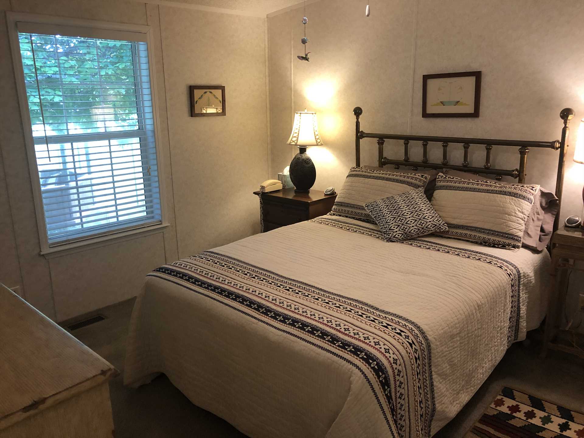                                                 Light decor and a ceiling fan keep the queen-sized bed in the second bedroom airy and comfy! Every inch of the house is climate-controlled with central air, too.