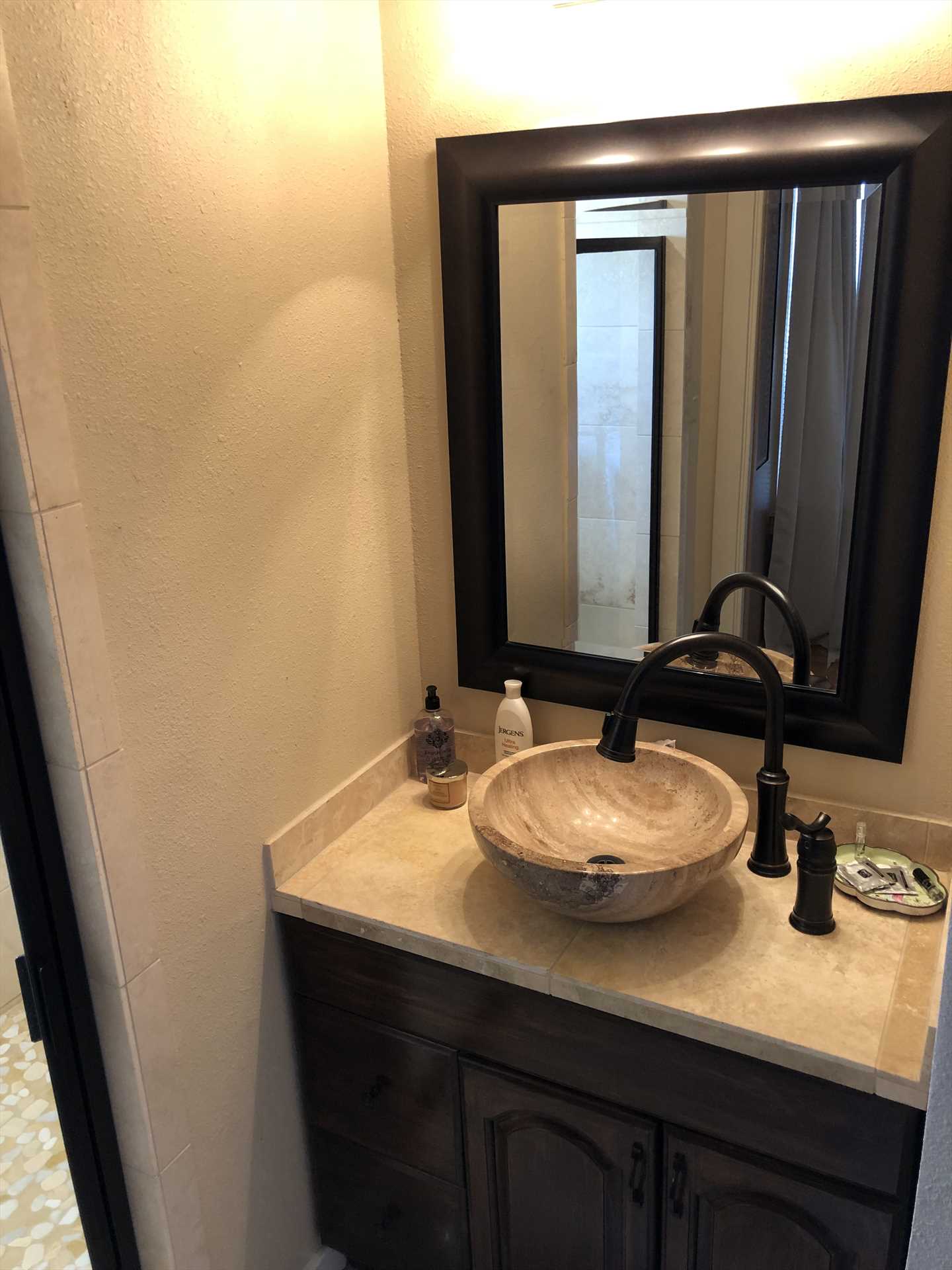                                                 The boldly-framed vanity mirror over the bowl-style sink add style touches to the master bath, there's nothing ordinary about any room here!