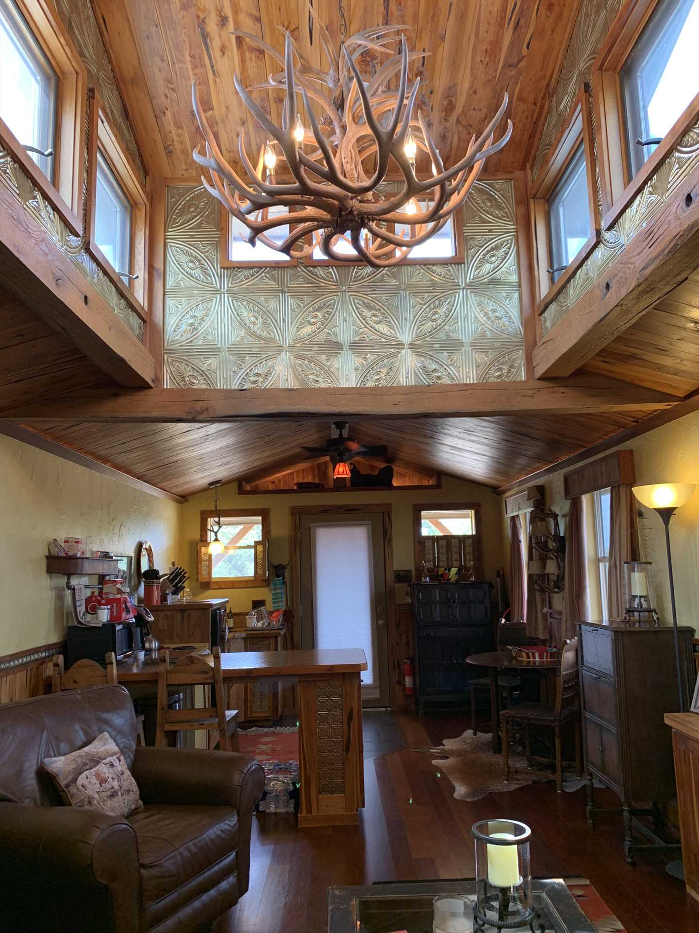                                                 The cabin's namesake antler chandelier is framed by high ceilings, tin panels, rich woodwork, and plenty of natural light.