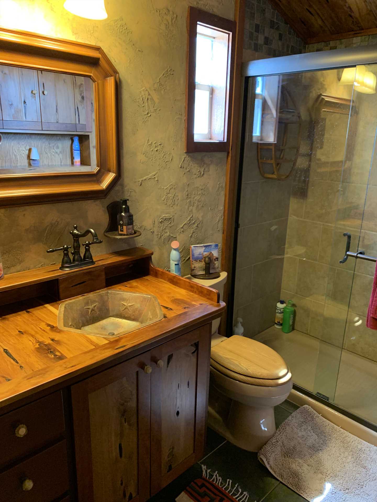                                                 The full bath features a shower stall, unique wood-accented vanity, and plenty of fluffy and clean linens.