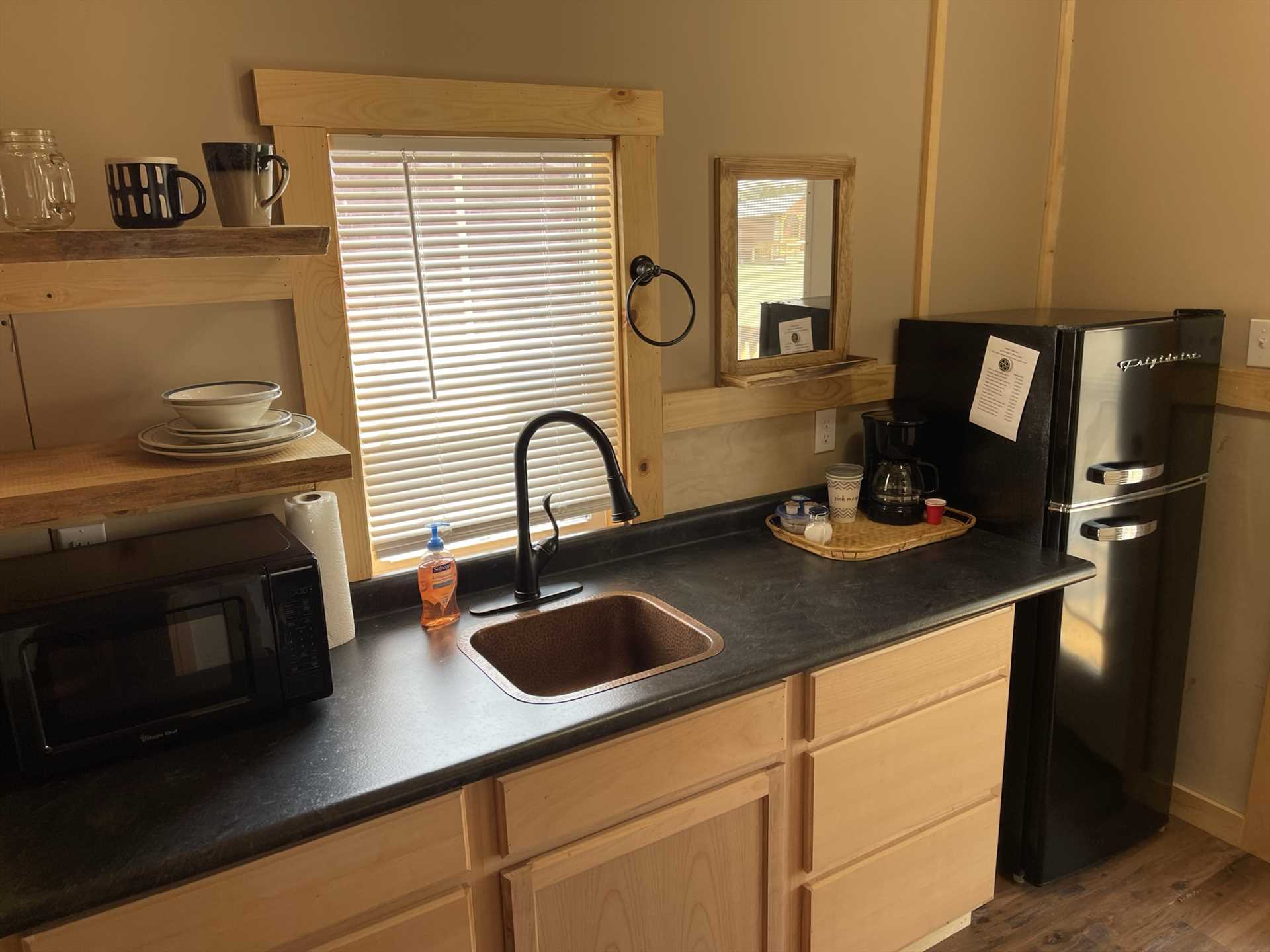                                                 A fridge, coffee maker, and microwave adorn the kitchen at the Hummingbird Cabin, as well as glasses and serving ware.